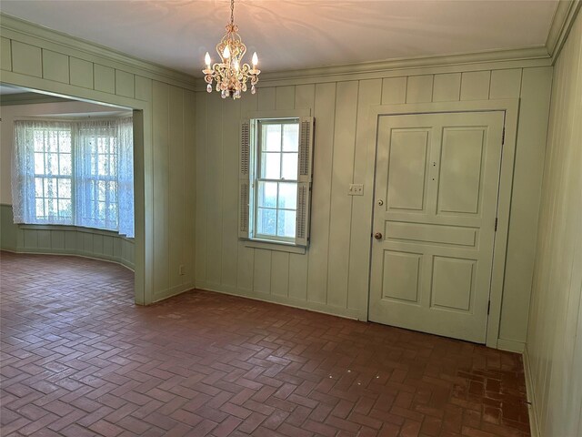 spare room with brick floor, a notable chandelier, and ornamental molding