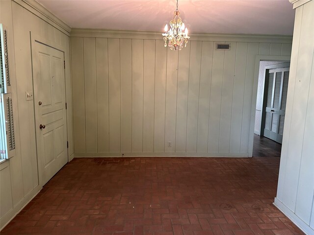 unfurnished dining area with a notable chandelier, visible vents, brick floor, and ornamental molding