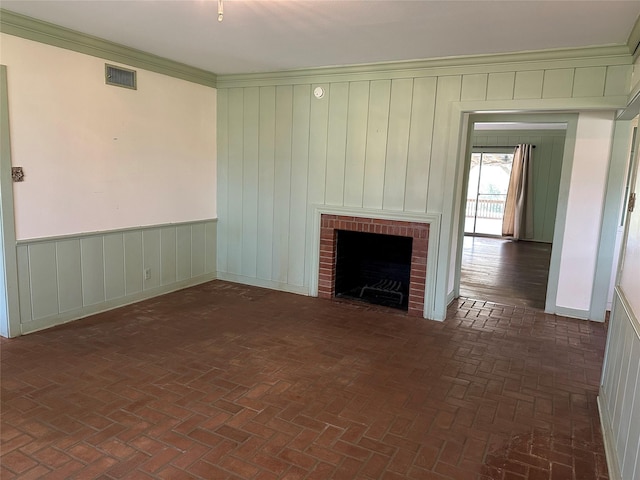 unfurnished living room with visible vents, a brick fireplace, brick floor, and ornamental molding