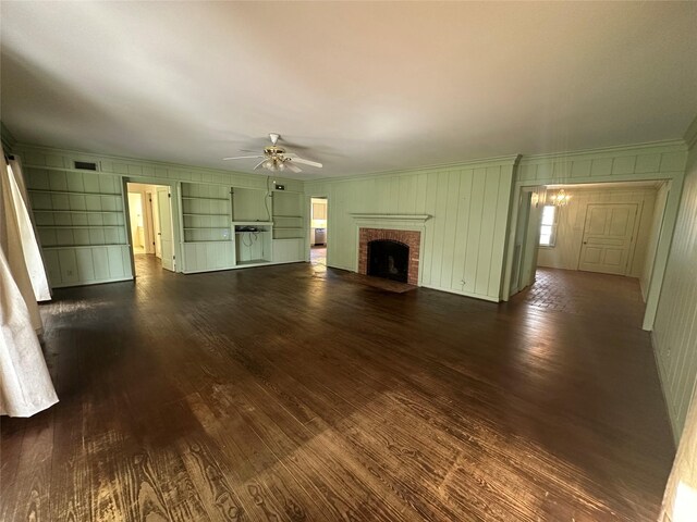 unfurnished living room featuring a ceiling fan, dark wood finished floors, a fireplace, and crown molding