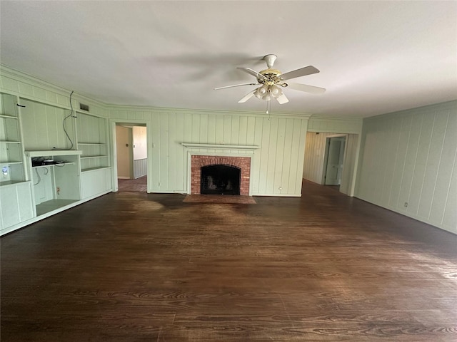 unfurnished living room with a brick fireplace, crown molding, ceiling fan, and dark wood-style flooring