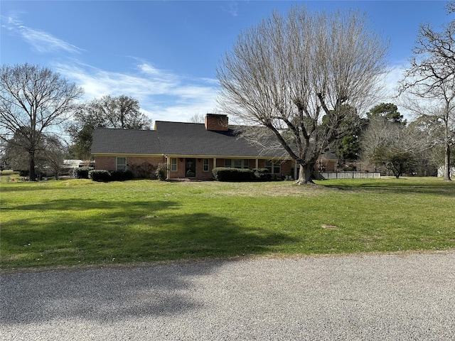 ranch-style house with a front lawn, brick siding, and a chimney