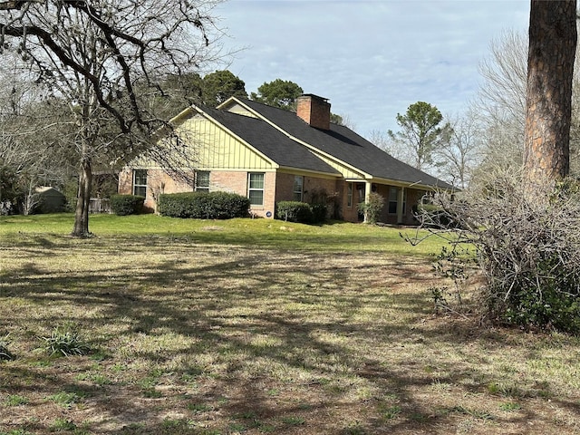 view of front of property with brick siding, board and batten siding, a chimney, and a front yard