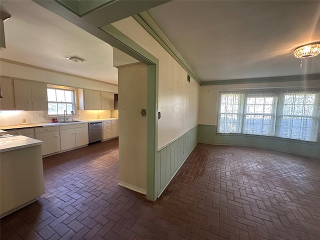 interior space featuring wainscoting, crown molding, brick floor, and stainless steel dishwasher