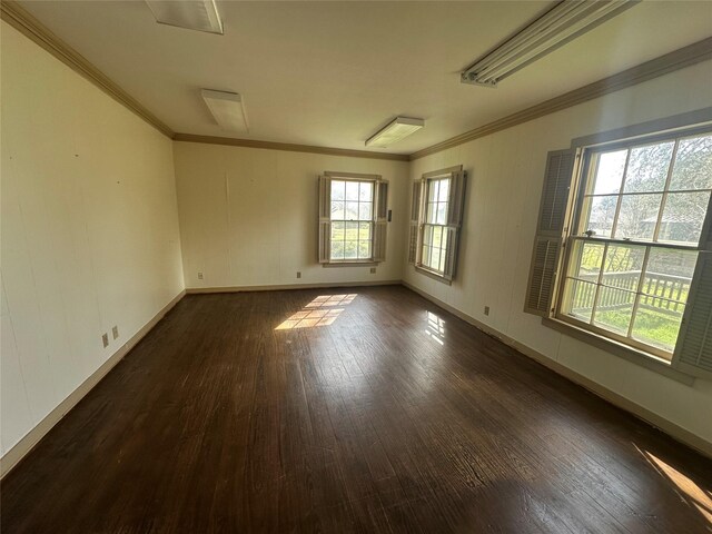 empty room featuring baseboards, crown molding, and dark wood-type flooring