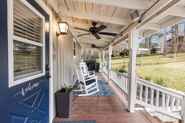 wooden terrace featuring a yard, covered porch, ceiling fan, and fence