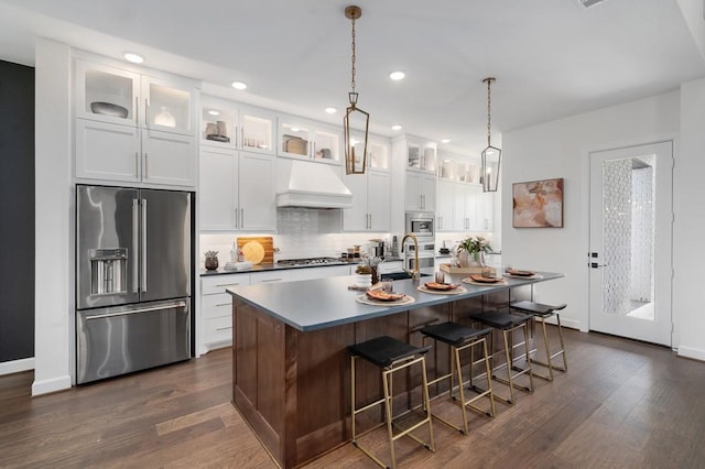 kitchen featuring stainless steel appliances, premium range hood, glass insert cabinets, and white cabinetry