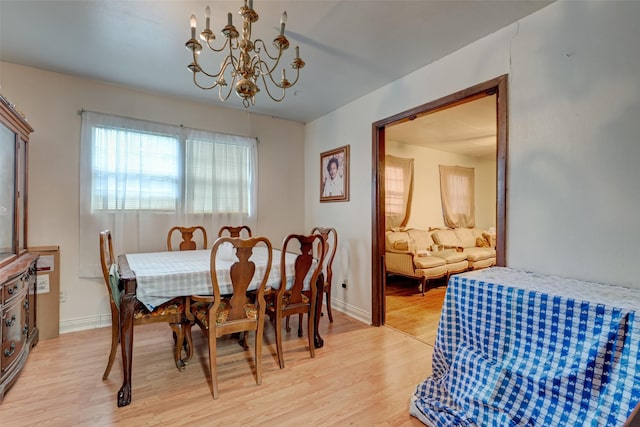 dining area featuring a notable chandelier, baseboards, and light wood-style floors