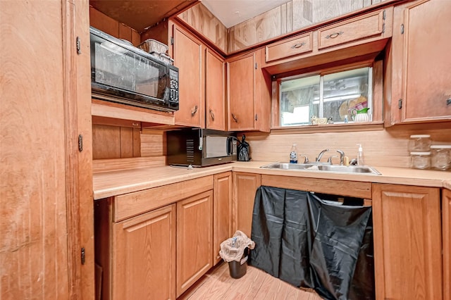 kitchen with brown cabinetry, black microwave, light countertops, and a sink