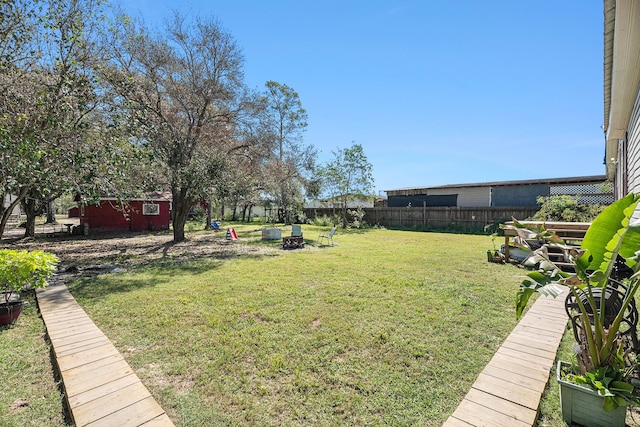 view of yard featuring a fire pit, an outbuilding, and a fenced backyard