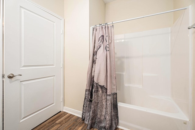 full bathroom featuring baseboards, wood finished floors, and shower / tub combo with curtain