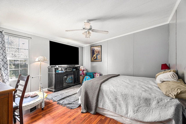 bedroom with ornamental molding, ceiling fan, a textured ceiling, and wood finished floors