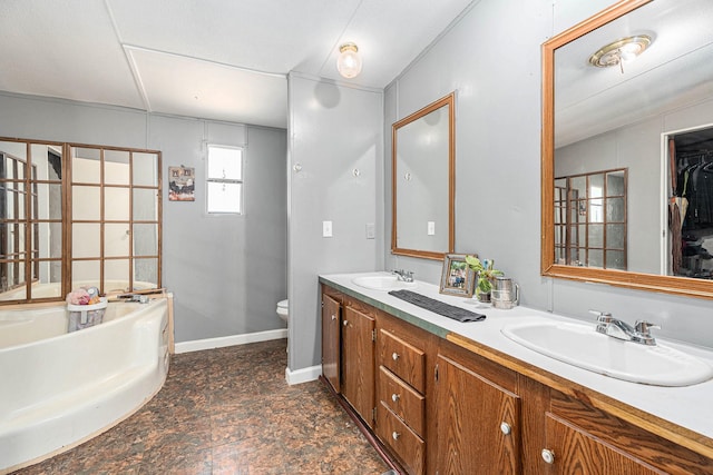 bathroom featuring baseboards, a garden tub, a sink, and toilet