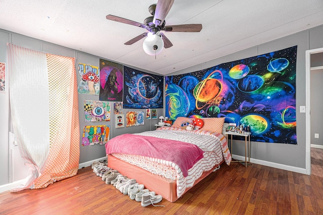 bedroom with a textured ceiling, wood finished floors, a ceiling fan, and baseboards