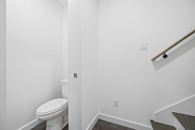 bathroom with toilet, baseboards, and wood finished floors