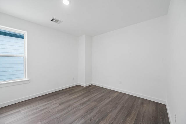 spare room with wood finished floors, visible vents, and baseboards