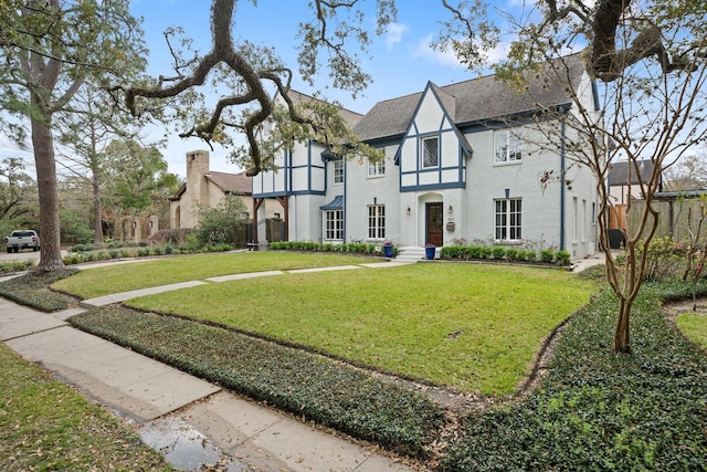 tudor house with a front yard and brick siding