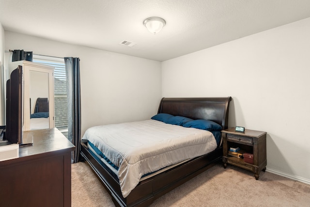 bedroom featuring baseboards, visible vents, and light carpet