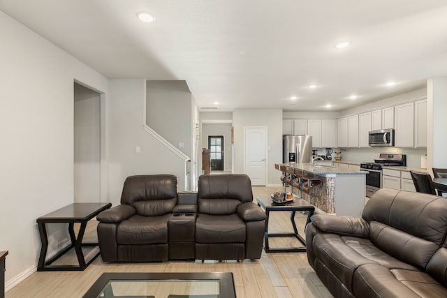 living room with recessed lighting, light wood-type flooring, and baseboards