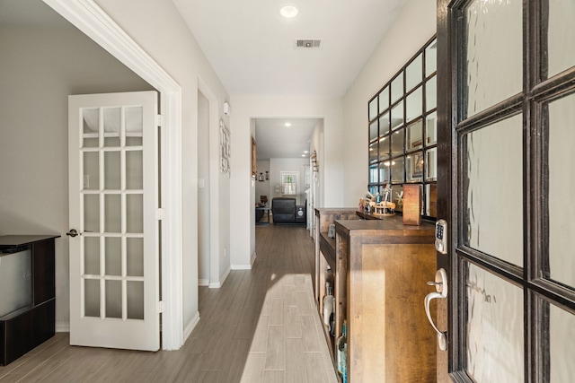 corridor with visible vents, baseboards, and wood finished floors