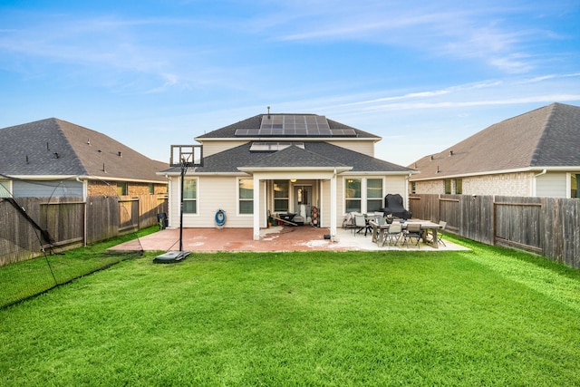 back of property with solar panels, a patio area, a yard, and a fenced backyard