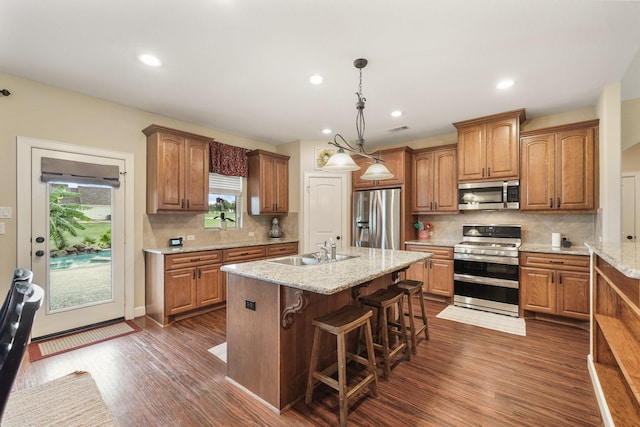 586 Ruby Dr, Bellville, TX 77418 - kitchen with stainless steel appliances, brown cabinets, a kitchen island with sink, and a sink