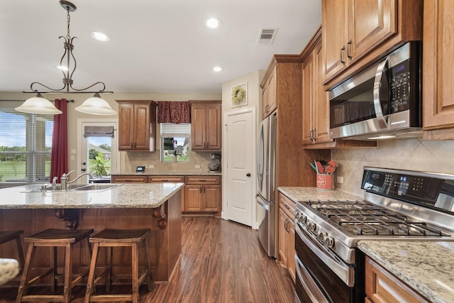 586 Ruby Dr, Bellville, TX 77418 - kitchen with visible vents, appliances with stainless steel finishes, hanging light fixtures, light stone countertops, and a sink