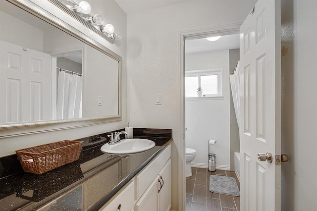 bathroom featuring baseboards, vanity, and toilet