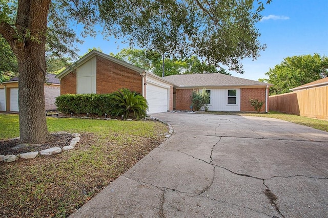 view of front of property featuring a garage, brick siding, driveway, and fence