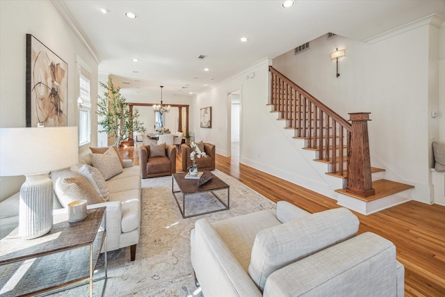 living area featuring crown molding, wood finished floors, visible vents, stairs, and an inviting chandelier