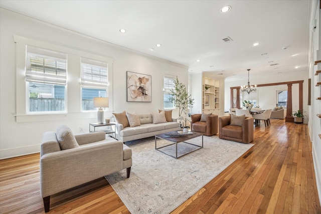 living room featuring a chandelier, light wood finished floors, recessed lighting, and crown molding