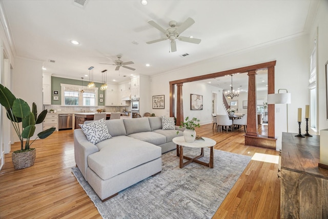 living area featuring light wood-style flooring, visible vents, a chandelier, and ornamental molding