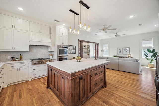 kitchen featuring white cabinets, premium range hood, visible vents, and stainless steel appliances