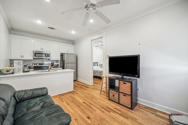 living room with ornamental molding, light wood-style flooring, visible vents, and a ceiling fan