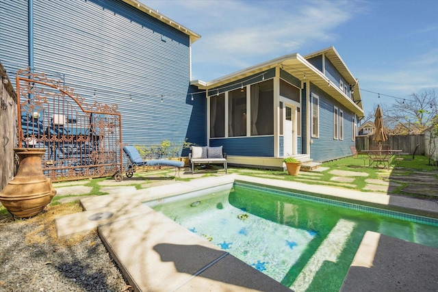 rear view of house featuring a sunroom, fence, and a patio