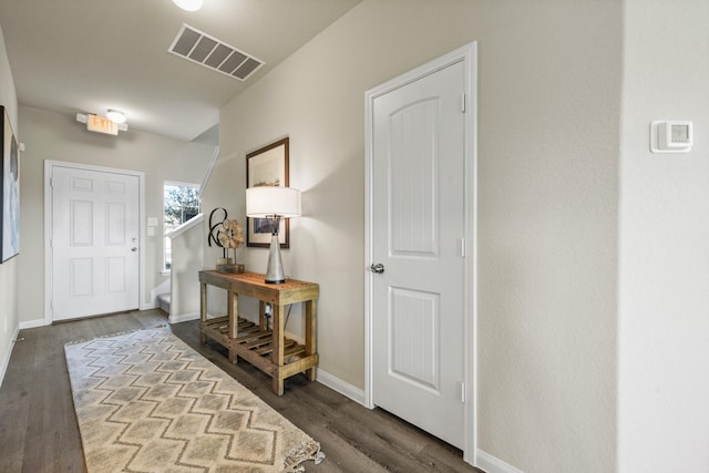 foyer with stairway, baseboards, visible vents, and wood finished floors