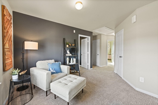 living area with attic access, baseboards, and light colored carpet