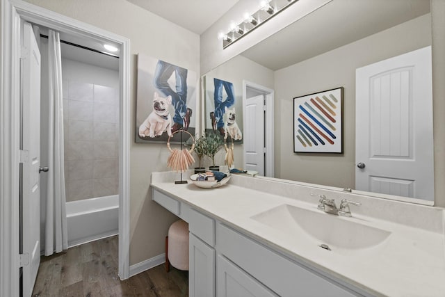 bathroom with shower / bath combination, vanity, baseboards, and wood finished floors