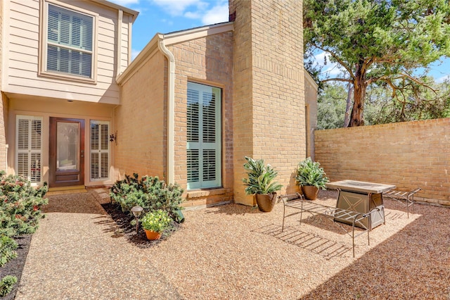 rear view of property featuring a patio, a fire pit, brick siding, fence, and a chimney