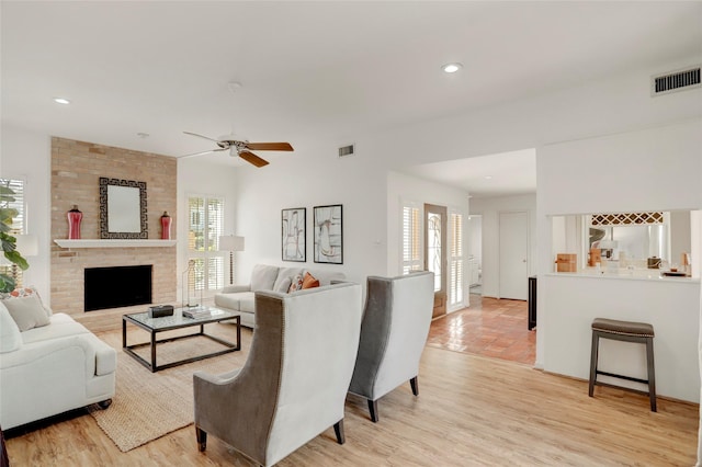 living room featuring a brick fireplace, visible vents, and a healthy amount of sunlight