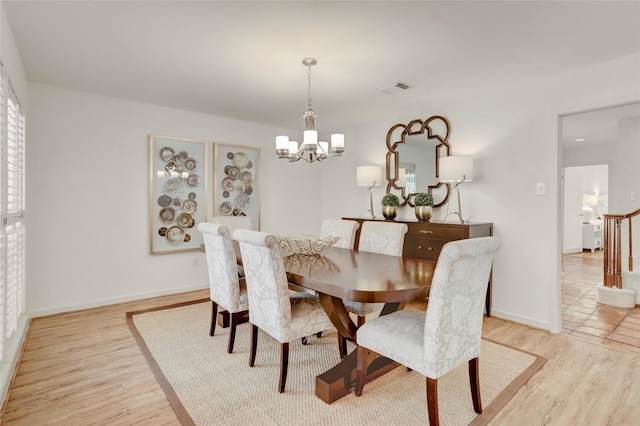 dining space featuring visible vents, light wood-style flooring, baseboards, and an inviting chandelier