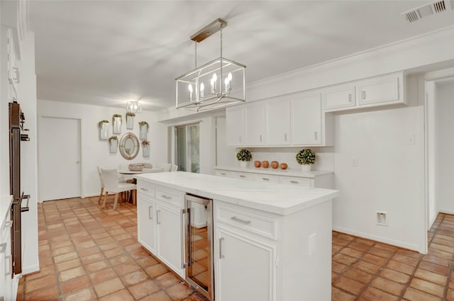 kitchen featuring beverage cooler, visible vents, a center island, white cabinetry, and pendant lighting