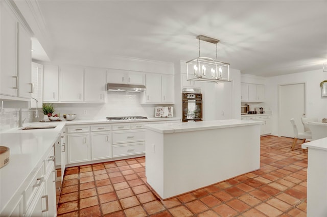 kitchen featuring under cabinet range hood, stovetop, backsplash, and oven