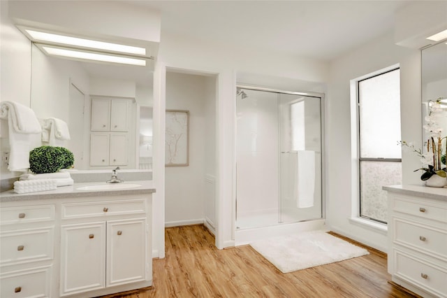 full bath featuring baseboards, a shower stall, vanity, and wood finished floors