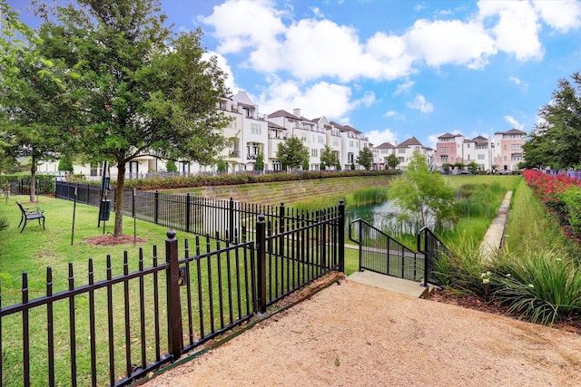 view of gate with a water view, a residential view, fence, and a yard