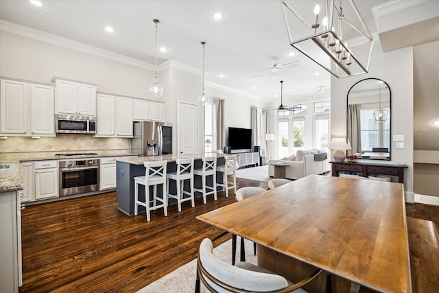 kitchen with light stone countertops, white cabinetry, open floor plan, appliances with stainless steel finishes, and a center island