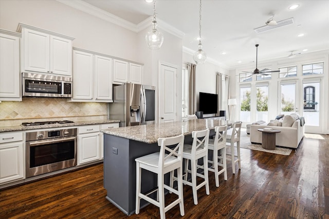 kitchen featuring stainless steel appliances, a center island, open floor plan, and white cabinetry