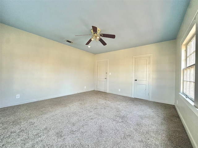 carpeted spare room with baseboards, visible vents, and ceiling fan