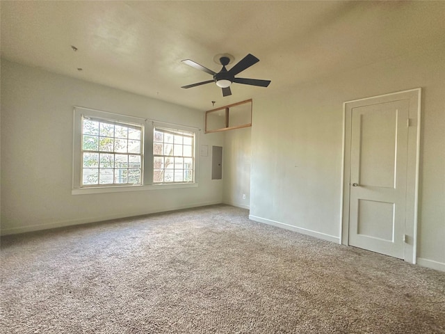 spare room with carpet floors, electric panel, ceiling fan, and baseboards