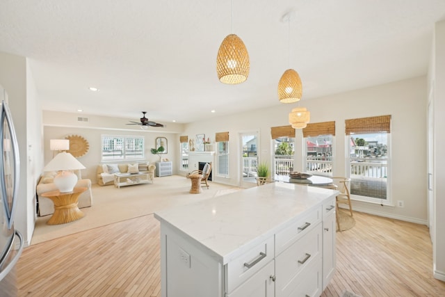 4105 Nueces Dr, Galveston, TX 77554 - kitchen with white cabinets, a kitchen island, open floor plan, decorative light fixtures, and light stone countertops